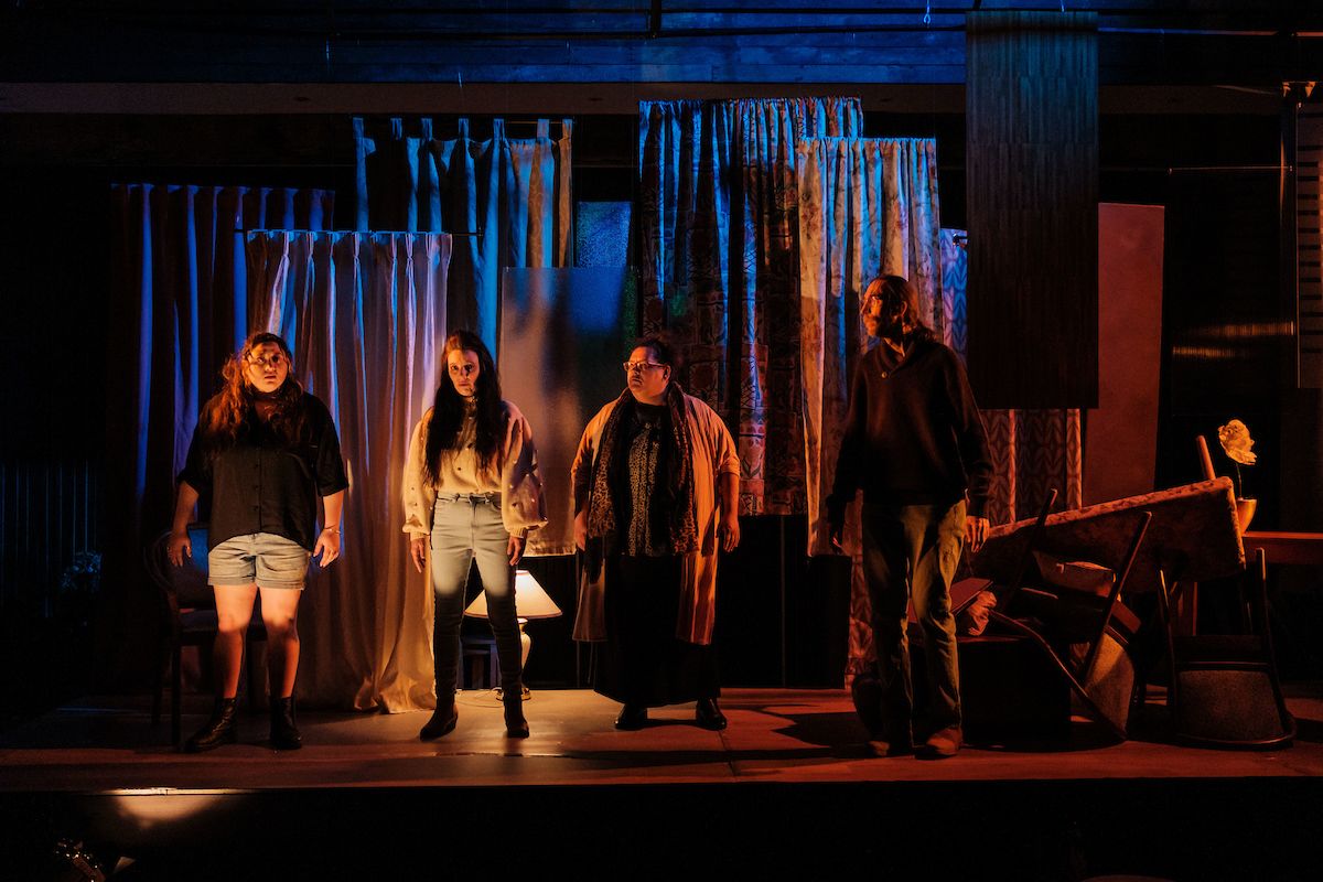 Four cast members of DUST, by Milk Crate Theatre, standing on stage in the middle of a performance