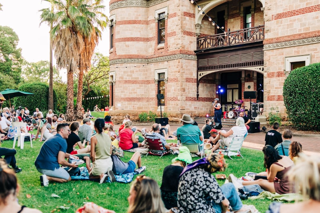 A crowd of people sitting on a lawn at Carclew