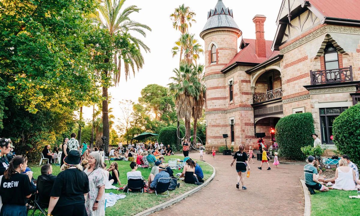 A crowd of people sitting on the lawn in front of the Carclew building